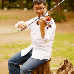 切り株に腰掛けてヴァイオリンを演奏している・いちろーたの写真